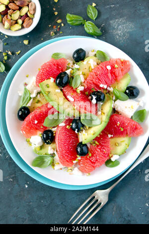 Salade d'avocat avec des pamplemousses, fromage feta, olives noires et à la pistache. Vue de dessus avec l'exemplaire de l'espace. Alimentation saine. Banque D'Images