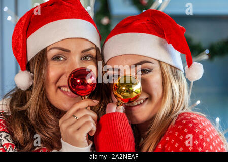 Portrait de deux jeunes soeur s'amuser faire des grimaces avec des boules de Noël Banque D'Images