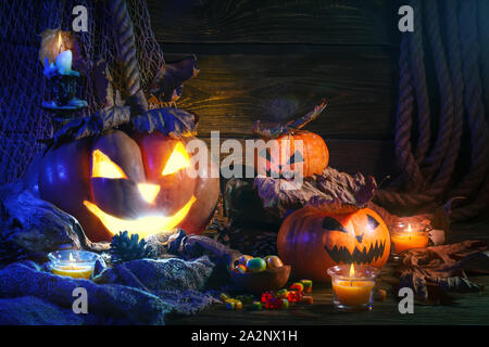 Citrouilles d'Halloween et des bonbons sur la table en bois dans la nuit. L'Halloween. Banque D'Images