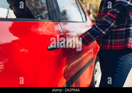 Voiture d'ouverture de porte. Femme ouvre voiture rouge avec clé Banque D'Images