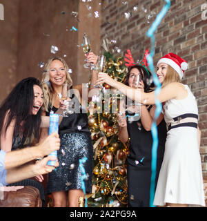 Des femmes heureuses qui s'amusent avec des confettis et du champagne au New Fête de l'année dans un loft moderne Banque D'Images