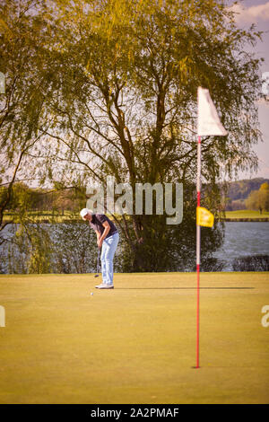 Golfeur aîné mise sur le vert. Banque D'Images