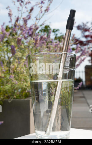 La paille dans l'acier inoxydable réutilisable utilisation dans un verre d'eau, USA Banque D'Images