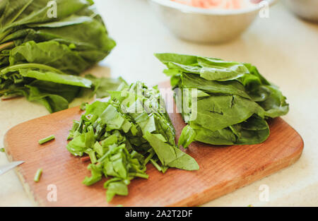 Les jeunes tranches d'oseille verte pour le borscht et salade se trouve sur une planche à découper, de style rustique, le matin dans la lumière du soleil. Copier l'espace. Banque D'Images