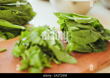 Les jeunes tranches d'oseille verte pour le borscht et salade se trouve sur une planche à découper, de style rustique, le matin dans la lumière du soleil. Copier l'espace. Banque D'Images