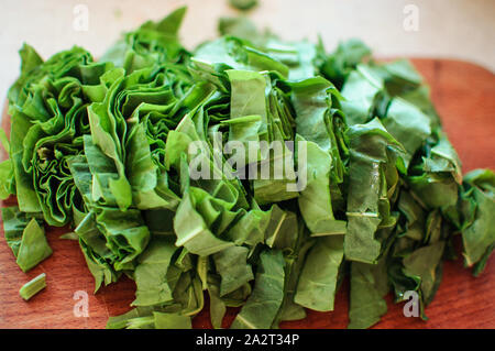 Les jeunes tranches d'oseille verte pour le borscht et salade se trouve sur une planche à découper, de style rustique, le matin dans la lumière du soleil. Copier l'espace. Banque D'Images