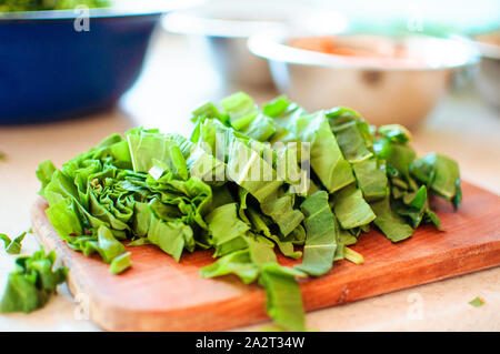 Les jeunes tranches d'oseille verte pour le borscht et salade se trouve sur une planche à découper, de style rustique, le matin dans la lumière du soleil. Copier l'espace. Banque D'Images