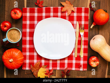 Plaque blanche vide de texte, nappe rouge, les citrouilles et les pommes contre le bois sombre. L'automne ou à l'automne fête de concept. Banque D'Images
