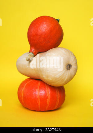 Trois citrouilles contre fond jaune. Un minimum d'automne à la mode composition. Concept d'halloween, jour de Thanksgiving vacances. Banque D'Images