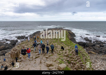Les touristes, grimpant sur la colonnes de basalte de la Chaussée des Géants en Irlande du Nord Banque D'Images