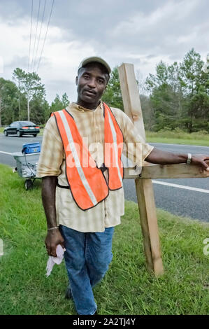 Homme portant une croix géante le long d'une autoroute dans le Nord de la Floride. Banque D'Images