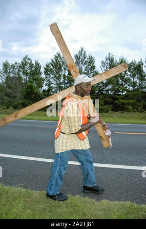 Homme portant une croix géante le long d'une autoroute dans le Nord de la Floride. Banque D'Images