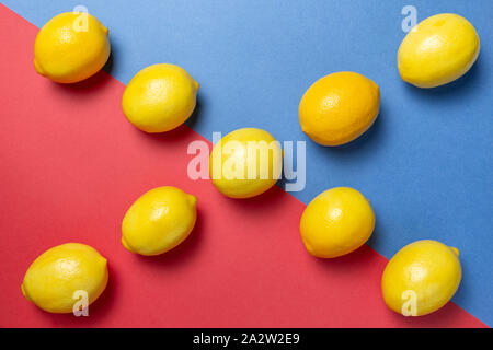 Citrons sur le bicolor rouge et le fond bleu. Mise à plat d'agrumes. Concept géométrique. Banque D'Images