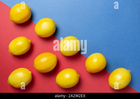 Citrons sur le bicolor rouge et le fond bleu. Mise à plat d'agrumes. Concept géométrique. Banque D'Images