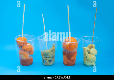 Une divers aliments de rue philippins sur une tasse en plastique avec des bâtons sur fond isolé bleu. Philippines L'alimentation de rue et leurs noms comme Kwek - Kwek Banque D'Images