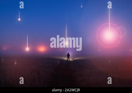 Concept d'OVNIS. Orbes lumineux, flottant au-dessus d'un champ misty la nuit. Avec un chiffre à au silhoutted lumières. Banque D'Images