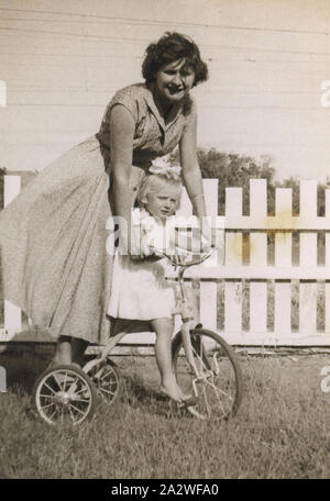 Photographie - Eileen & Susan Leech Équitation son tricycle dans la cour arrière, Frankston, vers 1954, photographie d'Eileen Leech et sa fille Susan équitation son tricycle dans son arrière-cour à Frankston, Melbourne, vers 1954. Susan avait émigré avec ses parents Eileen et James Leech à Melbourne depuis l'Angleterre en 1953 et ils sont retournés en Angleterre en 1956. La famille d'abord vécu au 19 rue Nelson Sandringham puis déplacé pour la majorité de leur séjour à Melbourne à 130 Dandenong Road Banque D'Images