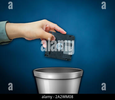Périphérique de stockage de l'ancienne génération de la technologie. Une main jetant une disquette dans la corbeille. Banque D'Images