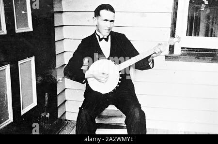 Négatif - Homme jouant un Banjo, Lake Goldsmith, Victoria, 1935, l'homme dans un smoking et cravate noire à jouer du banjo. Il y a une porte sur la gauche Banque D'Images