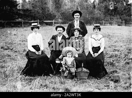 Négatif - Pique-nique, Victoria, vers 1905, deux hommes, trois femmes et un petit enfant à un pique-nique dans un champ. Il y a deux paniers pique-nique et de l'enfant est assis sur l'un d'eux. Il y a une forte ressemblance faciale entre les trois femmes - elles sont, sans doute, les soeurs Banque D'Images