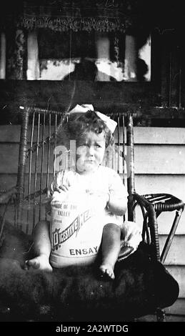 Négatif - 'Fierté de la vallée', Potrait d'enfant avec un sac de farine, Ensay digestif, Victoria, vers 1920, un petit enfant assis sur une chaise et tenant un sac de farine digestive qui est marqué comme 'Fierté de la vallée, produire des repas digestif Ensay Banque D'Images