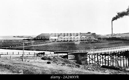 Négatif - Dennington, Warrnambool, Victoria, vers 1925, l'usine de l'entreprise se trouve limitée exclusive. Il y a un pont de bois sur une rivière au premier plan Banque D'Images