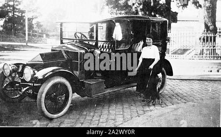 Négatif - Geelong, Victoria, vers 1920, une femme et le chien debout à côté d'une voiture. La voiture est sur une rue pavée en pierre bleue et il y a une clôture en fer forgé derrière elle Banque D'Images