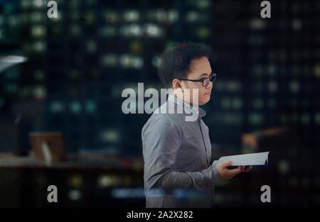 Jeune homme portant des lunettes et des manches à temporairement à autre chose distrait et pensez à quelque chose en lisant un livre. Banque D'Images