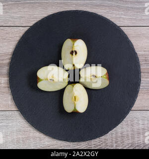 Une pomme coupé en quatre pointes sur une plaque noire Banque D'Images