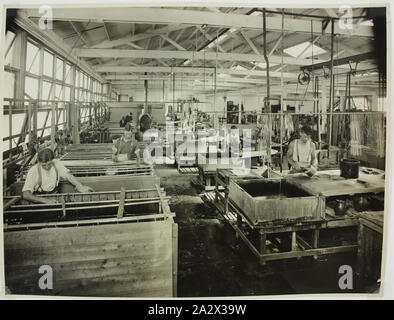 Photographie - Electrics Hecla Pty Ltd, ouvriers d'usine dans le département de placage, vers 1925, photographie en noir et blanc d'hommes travailleurs en usine des composants de l'appareil à un placage de l'usine de fabrication d'Hecla, probablement le Little Bourke Street locaux. Le long du mur gauche composants sont immergés dans des bacs de solution pour la galvanoplastie. vers la droite d'autres travailleurs des pièces propres. Le salon est éclairé par des fenêtres qui couvrent le mur de gauche, ce sont ouvertes pour permettre la ventilation. Un travailleur Banque D'Images