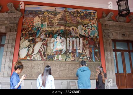 Les touristes à la recherche lors d'une peinture murale de Diego Rivera "La civilisation totonaque de la Jaguar dans Veracruz' dans le Palais National de Zocalo, Mexico. Banque D'Images