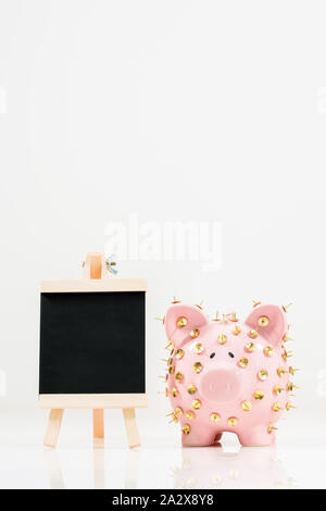 Image conceptuelle illustrant la protection des économies et des investissements montrant une banque de porc rose protégée par des piles de dessin et isolée contre le blanc. Banque D'Images