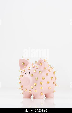 Image conceptuelle illustrant la protection des économies et des investissements montrant une banque de porc rose protégée par des piles de dessin et isolée contre le blanc. Banque D'Images