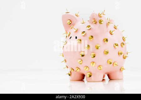 Image conceptuelle illustrant la protection des économies et des investissements montrant une banque de porc rose protégée par des piles de dessin et isolée contre le blanc. Banque D'Images