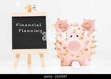 Image conceptuelle illustrant la protection des économies et des investissements montrant une banque de porc rose protégée par des piles de dessin et isolée contre le blanc. Banque D'Images