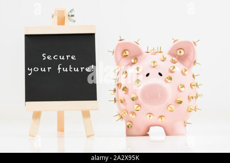 Image conceptuelle illustrant la protection des économies et des investissements montrant une banque de porc rose protégée par des piles de dessin et isolée contre le blanc. Banque D'Images