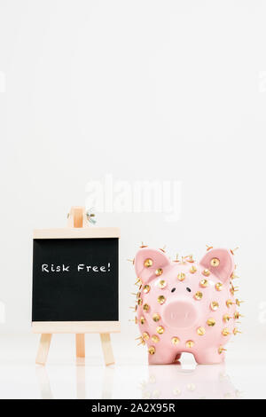 Image conceptuelle illustrant la protection des économies et des investissements montrant une banque de porc rose protégée par des piles de dessin et isolée contre le blanc. Banque D'Images