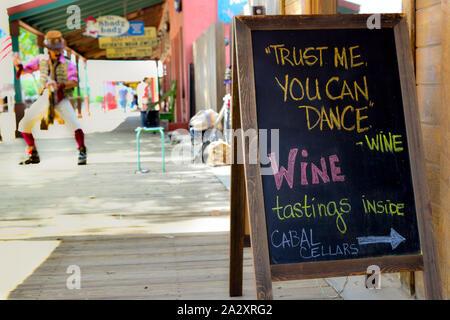 Panneau signe la promotion wine merchant a funny quote alors que l'interprète de danse de rue à proximité sur le trottoirs de bois de Tombstone, en Arizona, légendaire Banque D'Images