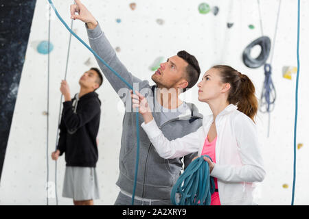 Les jeunes grimpeurs instructeur montrant les cordes au mur intérieur Banque D'Images