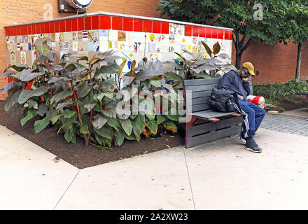 Un homme noir est assis sur un banc de parc en ville de l'Ohio, un gentifying rapidement près de Cleveland, Ohio, USA. Banque D'Images