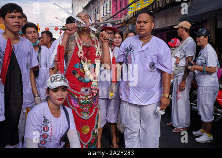 Une procession pendant le Festival végétarien dans la ville de Phuket, Thaïlande, avec un participant montrant une épée percée dans sa joue Banque D'Images