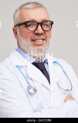 Portrait of mature médecin avec barbe grise et à lunettes smiling at camera avec stéthoscope autour du cou Banque D'Images