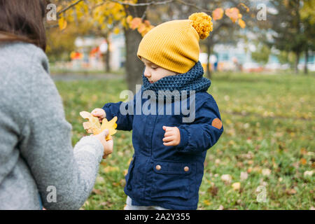 Mignon bébé garçon mode dans les tenues de explore le monde avec la mère à l'automne nature park Banque D'Images