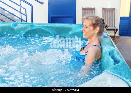 Middle aged woman le bain dans une baignoire avec des bulles Banque D'Images