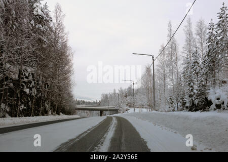 La conduite dans le pays merveilleux de l'hiver appelé la Finlande en hiver. Sur cette photo vous pouvez voir la route glacée et beaucoup de neige au sol et de la forêt autour de lui. Banque D'Images