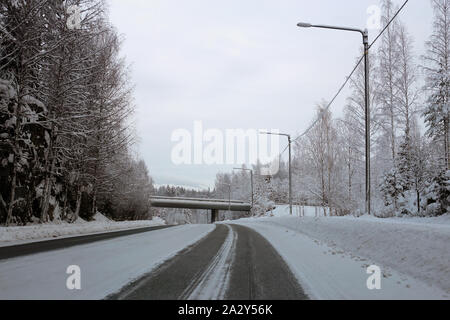 La conduite dans le pays merveilleux de l'hiver appelé la Finlande en hiver. Sur cette photo vous pouvez voir la route glacée et beaucoup de neige au sol et de la forêt autour de lui. Banque D'Images