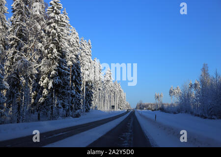 La conduite dans le pays merveilleux de l'hiver appelé la Finlande en hiver. Sur cette photo vous pouvez voir la route glacée et beaucoup de neige au sol et de la forêt autour de lui. Banque D'Images