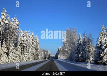 La conduite dans le pays merveilleux de l'hiver appelé la Finlande en hiver. Sur cette photo vous pouvez voir la route glacée et beaucoup de neige au sol et de la forêt autour de lui. Banque D'Images