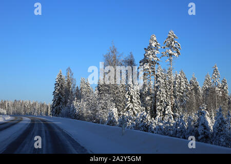 La conduite dans le pays merveilleux de l'hiver appelé la Finlande en hiver. Sur cette photo vous pouvez voir la route glacée et beaucoup de neige au sol et de la forêt autour de lui. Banque D'Images