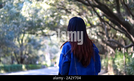 Belle jeune fille en robe bleue à la recherche d'arbres à Banque D'Images